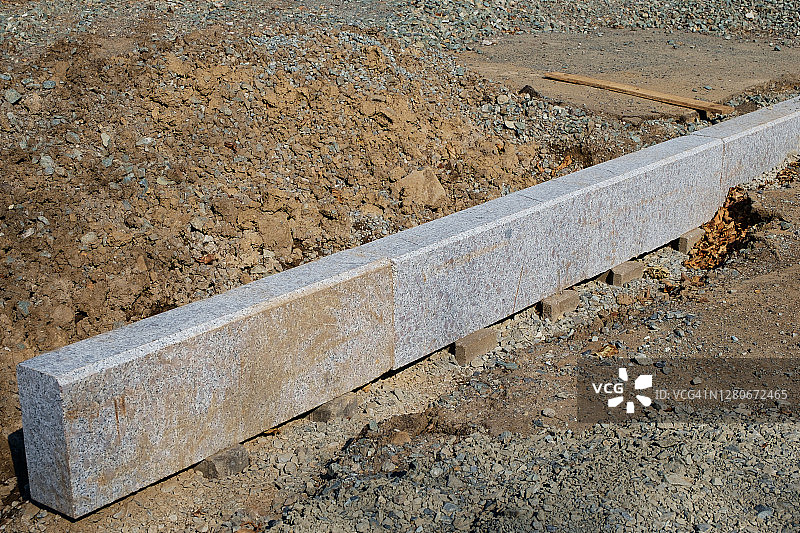 建设工作。安装在排水沟上的花岗石板制成的路缘。图片素材