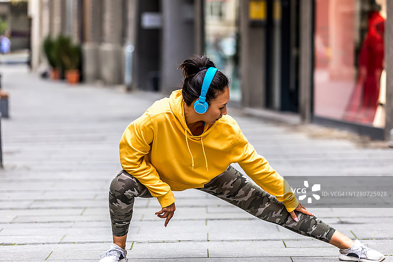 适合亚洲人在城市晨跑前做伸展运动图片素材