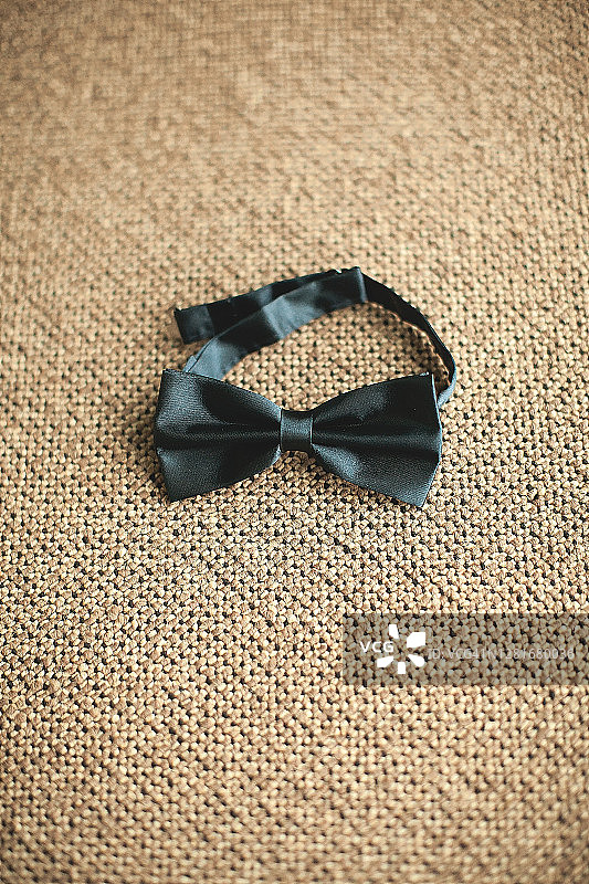 黑色领结，男士、新郎或商人的时尚配饰，特写。为婚礼当天的新郎做准备。模糊的背景图片素材