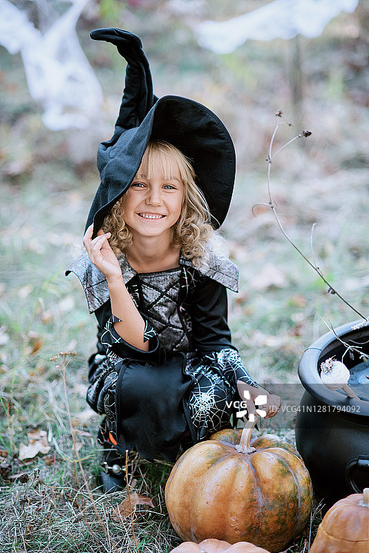 美丽的女孩女巫。小女孩穿着万圣节服装在户外庆祝，并有乐趣。孩子们不给糖就捣蛋图片素材