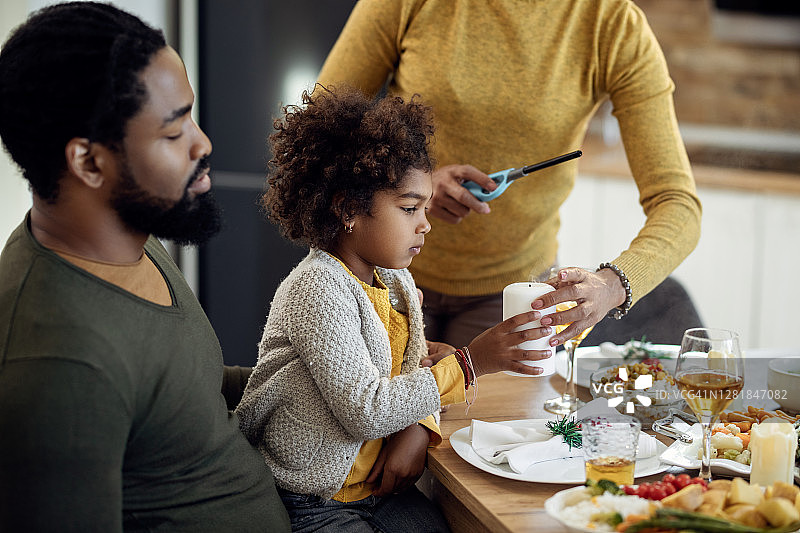非裔美国家庭在圣诞午餐餐桌上使用蜡烛。图片素材