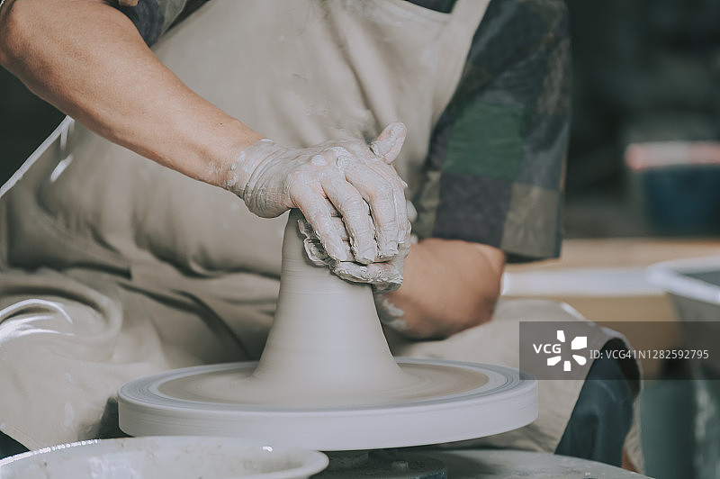亚洲华人高级泥塑艺术家在他的工作室与纺织陶轮工作图片素材
