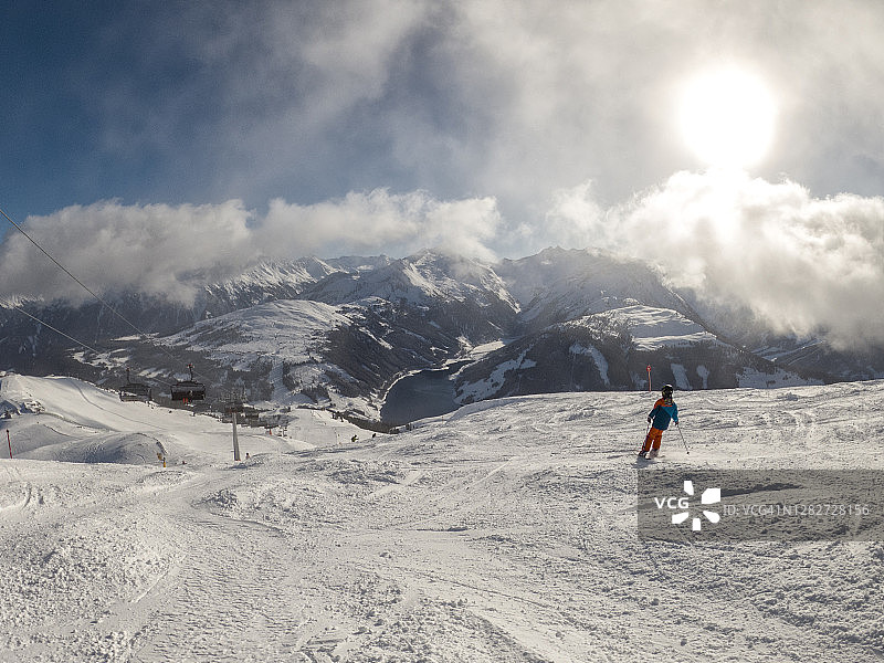 一个孤独的男孩在奥地利的冬季阿尔卑斯上，在梅洛芬的蒂罗尔滑雪胜地滑雪图片素材