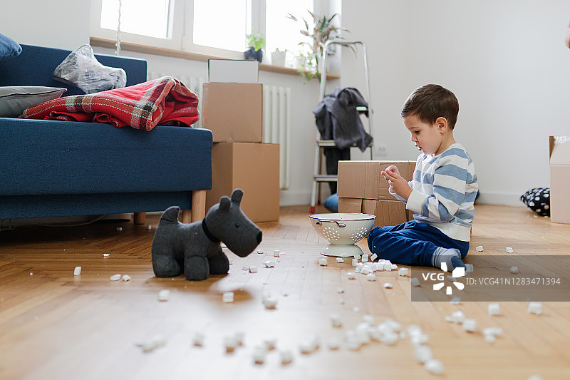 小男孩在地板上玩，盒子中间放着包装的花生和漏勺图片素材