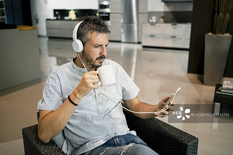 商人通过耳机听音乐，同时使用智能手机在办公室图片素材