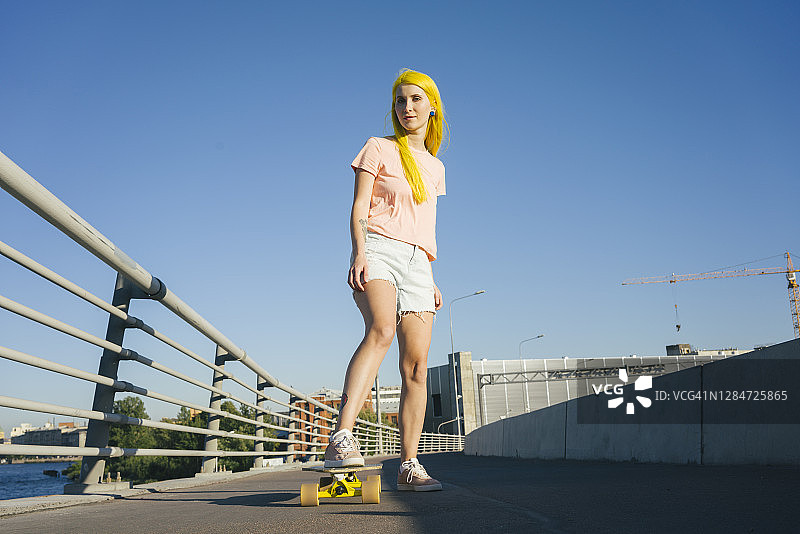 在晴朗的日子里，女子站在滑板上图片素材