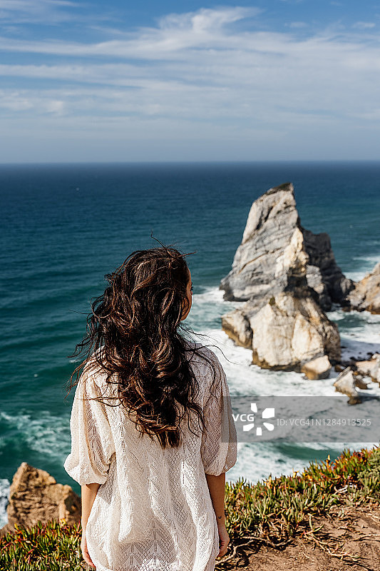 一名女子坐在悬崖顶上，葡萄牙普拉亚达熊星座图片素材