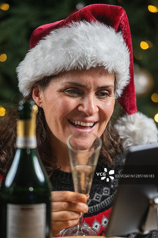 微笑成熟的女人用一杯香槟向她的家人用电话会议图片素材