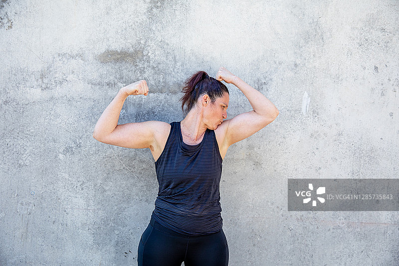 一个运动员的肖像，强壮的女人在黑色背心显示她的肌肉图片素材