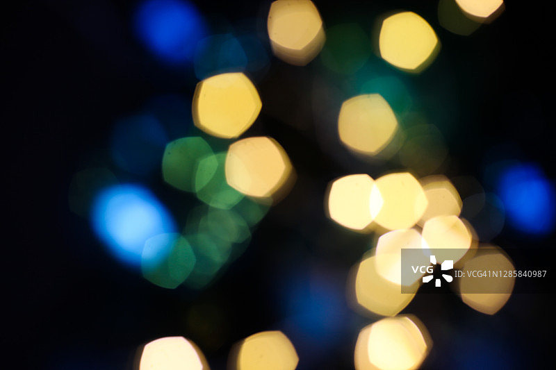 散焦蓝色、绿色和金色的光模糊了散焦。黑色圣诞或新年的节日背景。图片素材