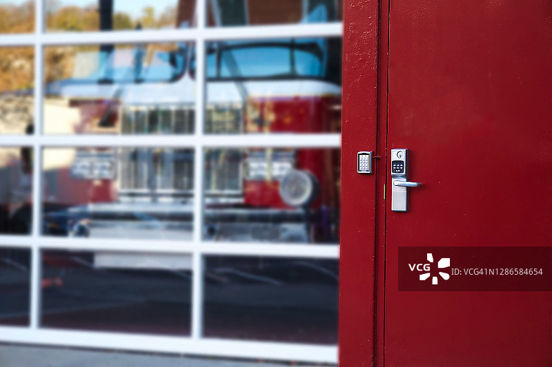 传统的红色消防站门和玻璃车库门后消防车的部分视图图片素材