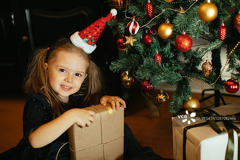 快乐的小女孩早上在圣诞树上带着礼物图片素材