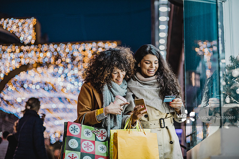两个女性朋友用手机和信用卡在网上购物图片素材