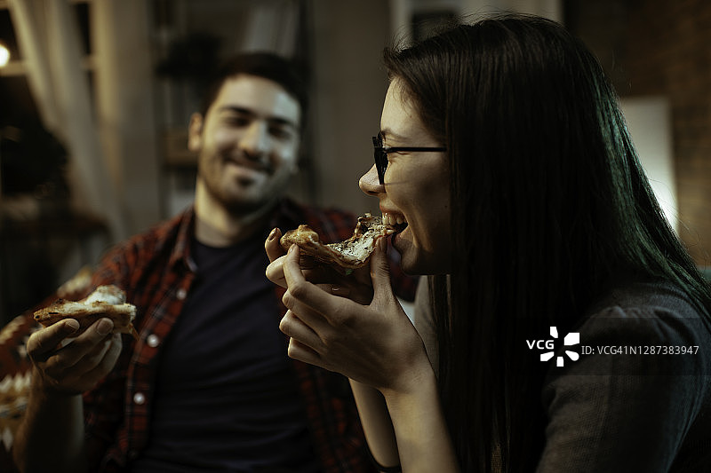 幸福的夫妇在家吃披萨。图片素材