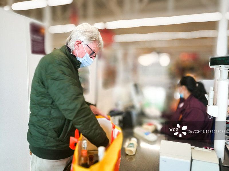 戴着防护口罩的老人在超市结账处图片素材