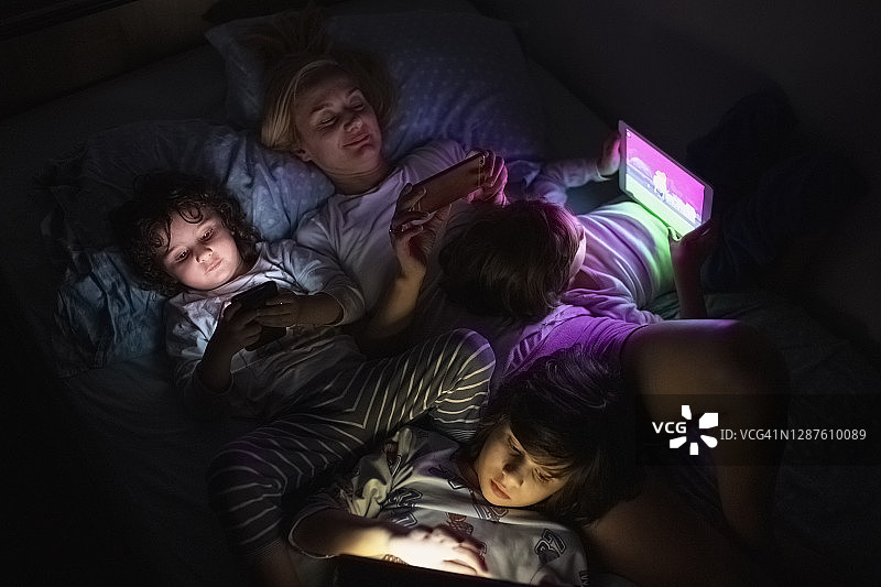 母亲和她的孩子在黑暗中寻找数字平板电脑图片素材
