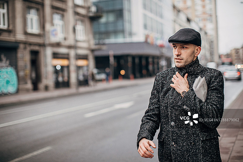 一个男人穿着温暖的现代外套走在城市的街道上图片素材