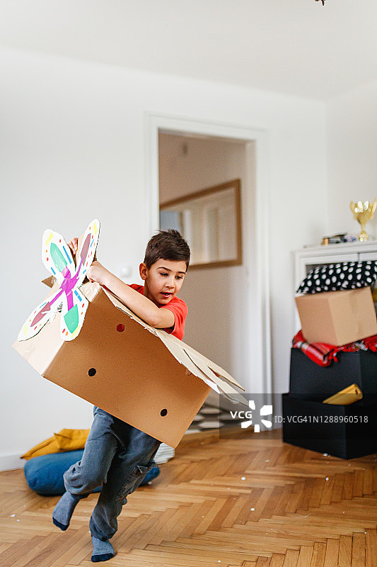 男孩假装开飞机，穿着带螺旋桨的纸板箱图片素材