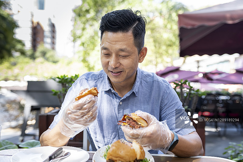 亚洲男子在户外吃汉堡图片素材