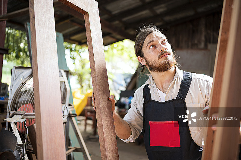 专业的Hipster木工在车间检查木架和工件。小企业，家庭改善。图片素材