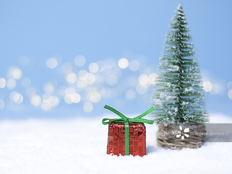 圣诞礼物在白雪覆盖的大地上。圣诞树。圣诞彩灯用散景照明图片素材