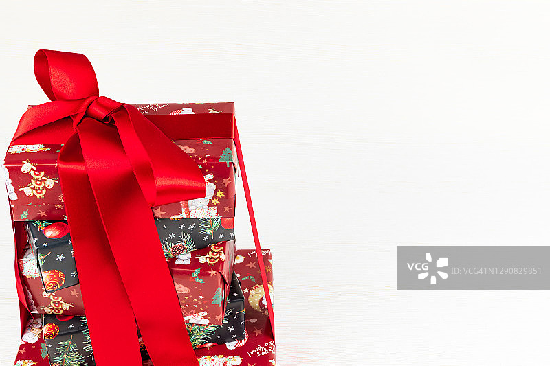 用红缎带绑着的彩色圣诞盒子和礼物堆放在白色的木头桌子上图片素材