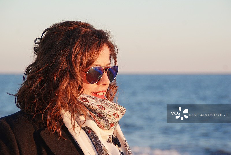 一个美丽的女人戴着太阳镜站在海边，马拉加，安达卢西亚，西班牙图片素材