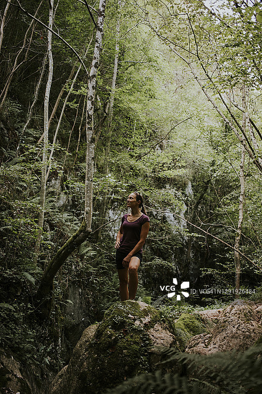 被绿树包围的女人在森林里探险图片素材