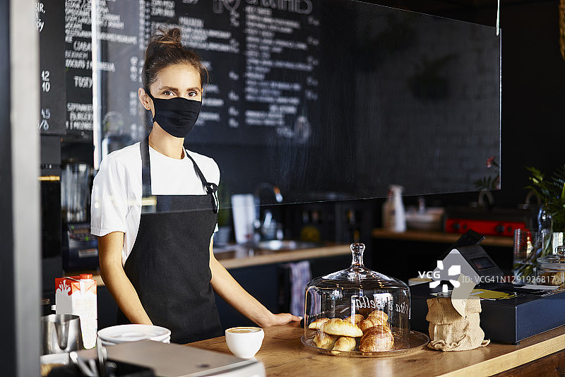 在咖啡店工作的女服务员戴着防护口罩的肖像图片素材
