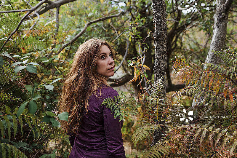 西班牙马德里，一名女子在森林里的植物间行走时，眼睛看向别处图片素材