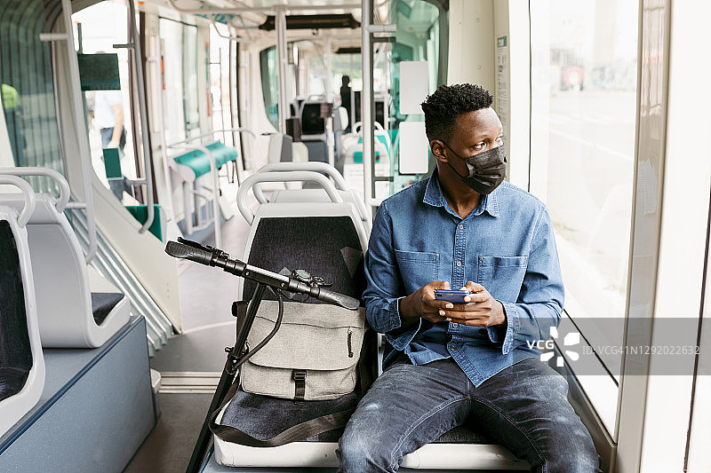流感期间乘坐火车时用智能手机看窗外的男性通勤者图片素材