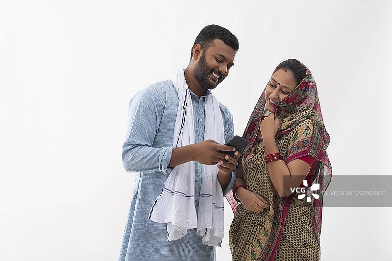 一个农村的丈夫和妻子看着手机和笑图片素材
