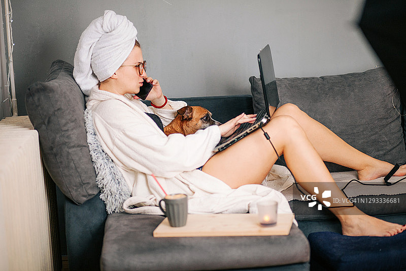 在家和她的狗一起工作的妇女图片素材