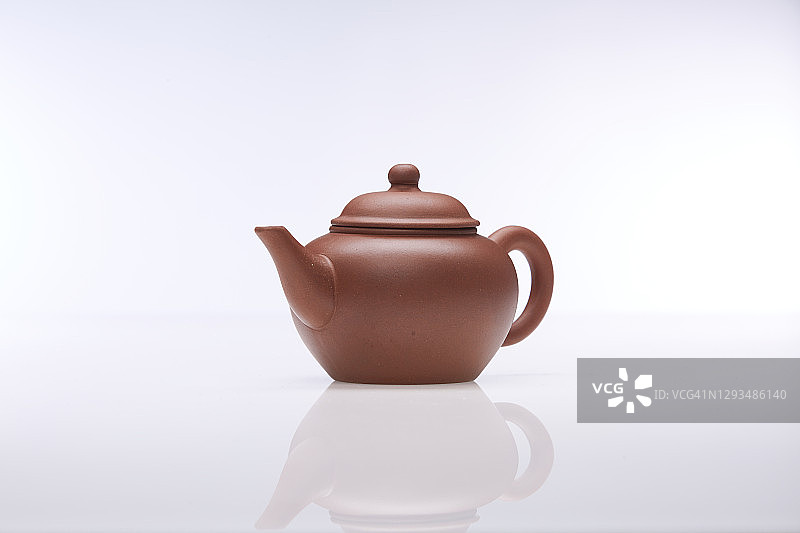 白色背景上的棕色粘土茶壶，工作室拍摄。图片素材