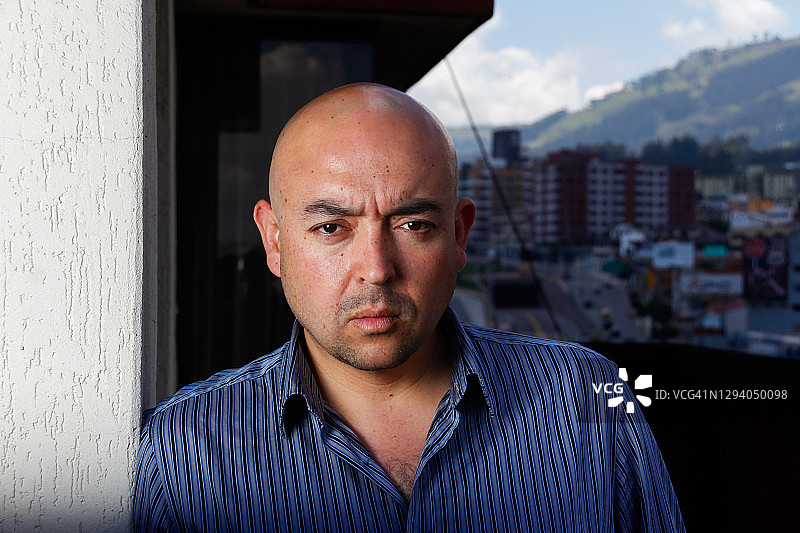 一幅严肃的男子靠在墙上的肖像，背景是厄瓜多尔首都基多图片素材
