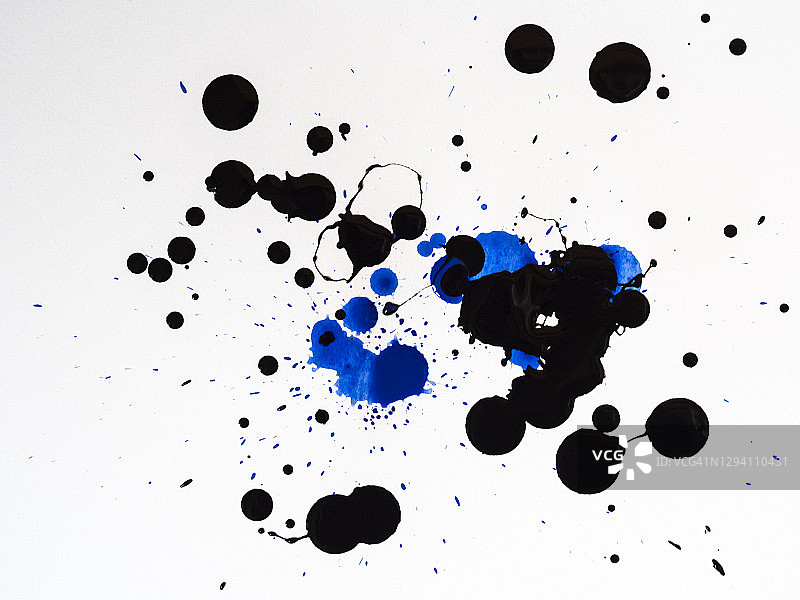 抽象的背景，黑色和蓝色的颜料滴在白色的画布上。图片素材
