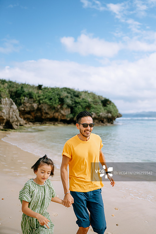 父亲和小女儿在日本热带海滩上跑步图片素材