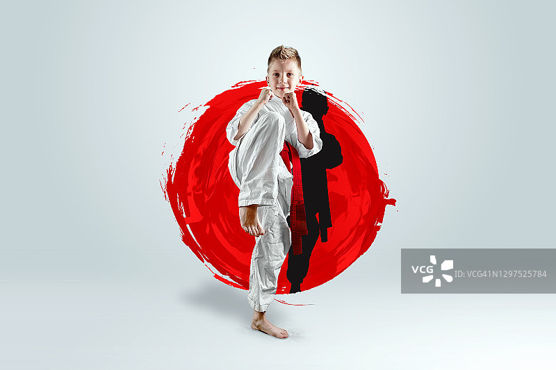 一个男孩的全身肖像在白色和服与红色的背景下的一个红圈的皮带。空手道概念，训练，目标，训练，成就。图片素材