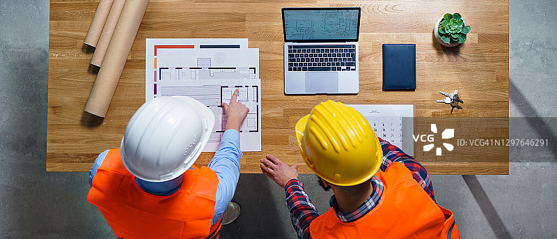 俯视图的工程师与平板电脑和蓝图工作在办公室办公桌。图片素材