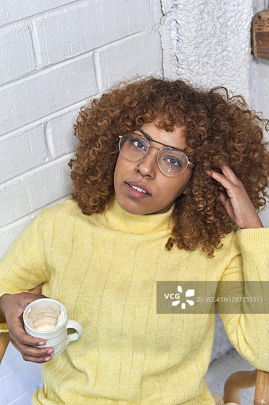 一个女人在咖啡馆里拿着咖啡杯，手插着头发图片素材