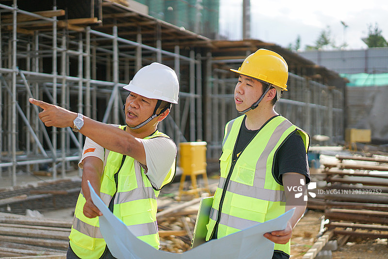 两名亚洲男性工程师正在一个建筑工地看图纸图片素材