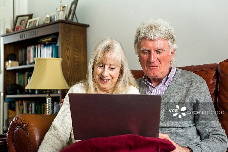老夫妇在家里用笔记本电脑和家人视频通话图片素材