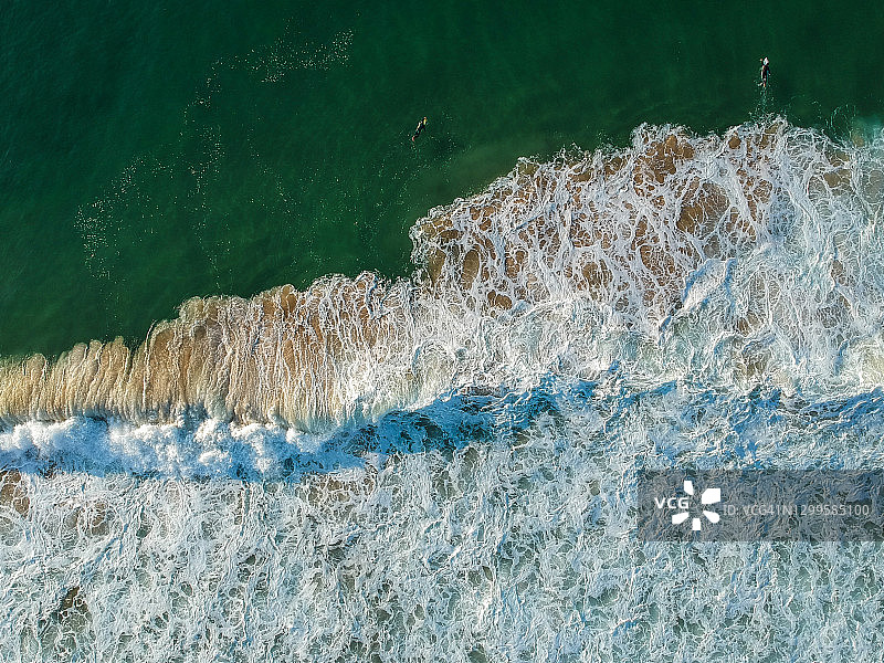无人机拍摄的美丽的蓝绿色海浪在沙滩上破碎。航拍的金色海滩图片素材