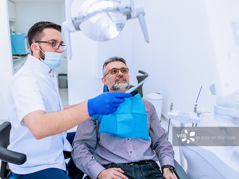 牙医向一位男性病人解释牙齿x光片图片素材