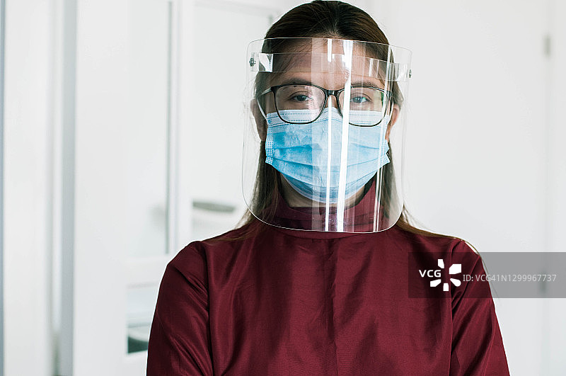 一名身穿防护服、面罩和面罩的年轻女前线医生在医疗诊所图片素材