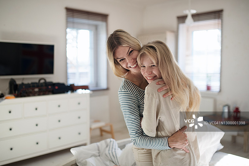母亲和小女儿在室内的卧室里，在床上拥抱。图片素材