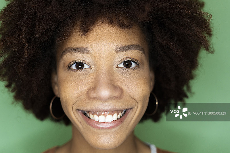 在新的阁楼公寓里，快乐的非洲裔妇女靠在绿色的墙上图片素材