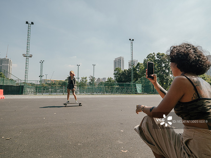 亚洲女孩在公园练习滑板。图片素材