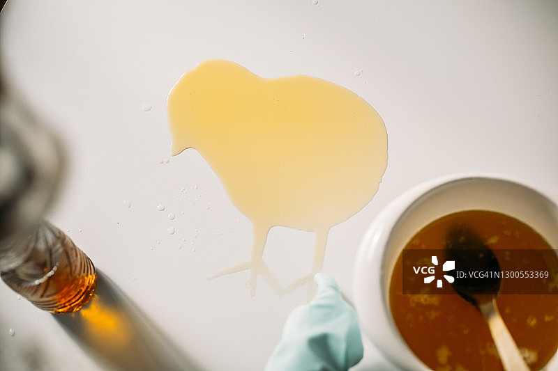 在做肥皂的时候，一只手在手套上画了一只小鸡在洒在桌上的油上图片素材