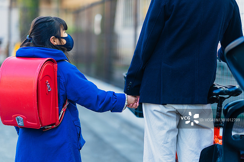 早晨，母亲和小学生一起走在街上。母亲去上班，女儿去上学图片素材